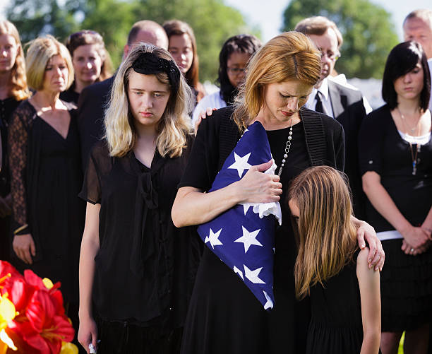 A mother and two children standing graveside at a funeral.